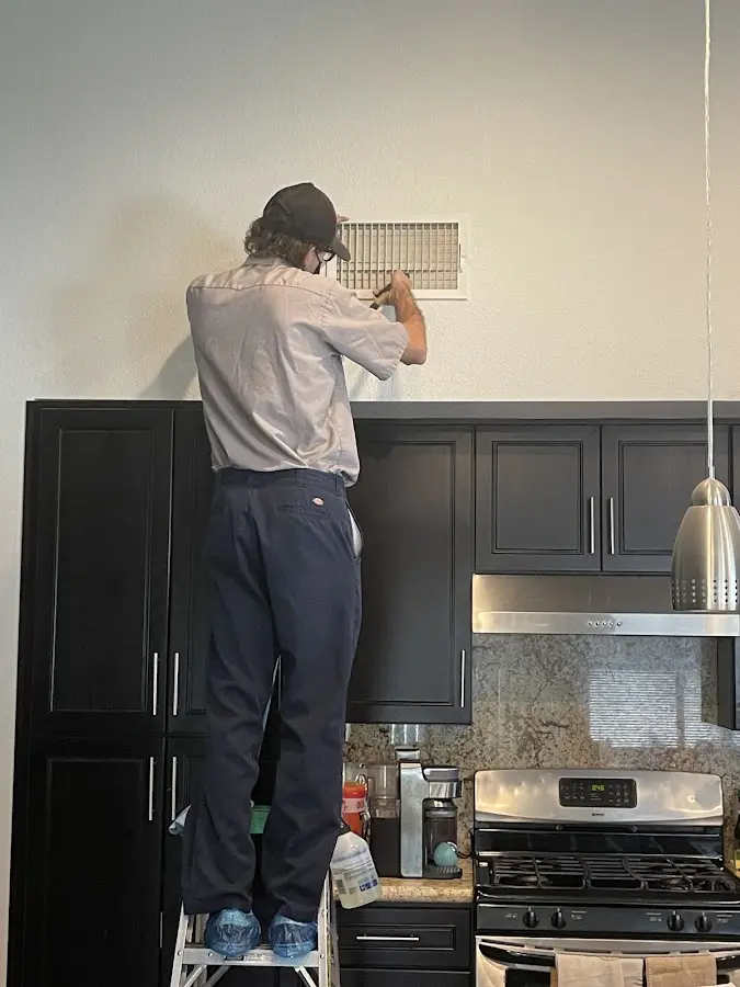 Technician inspecting an air vent during HVAC service in Alameda